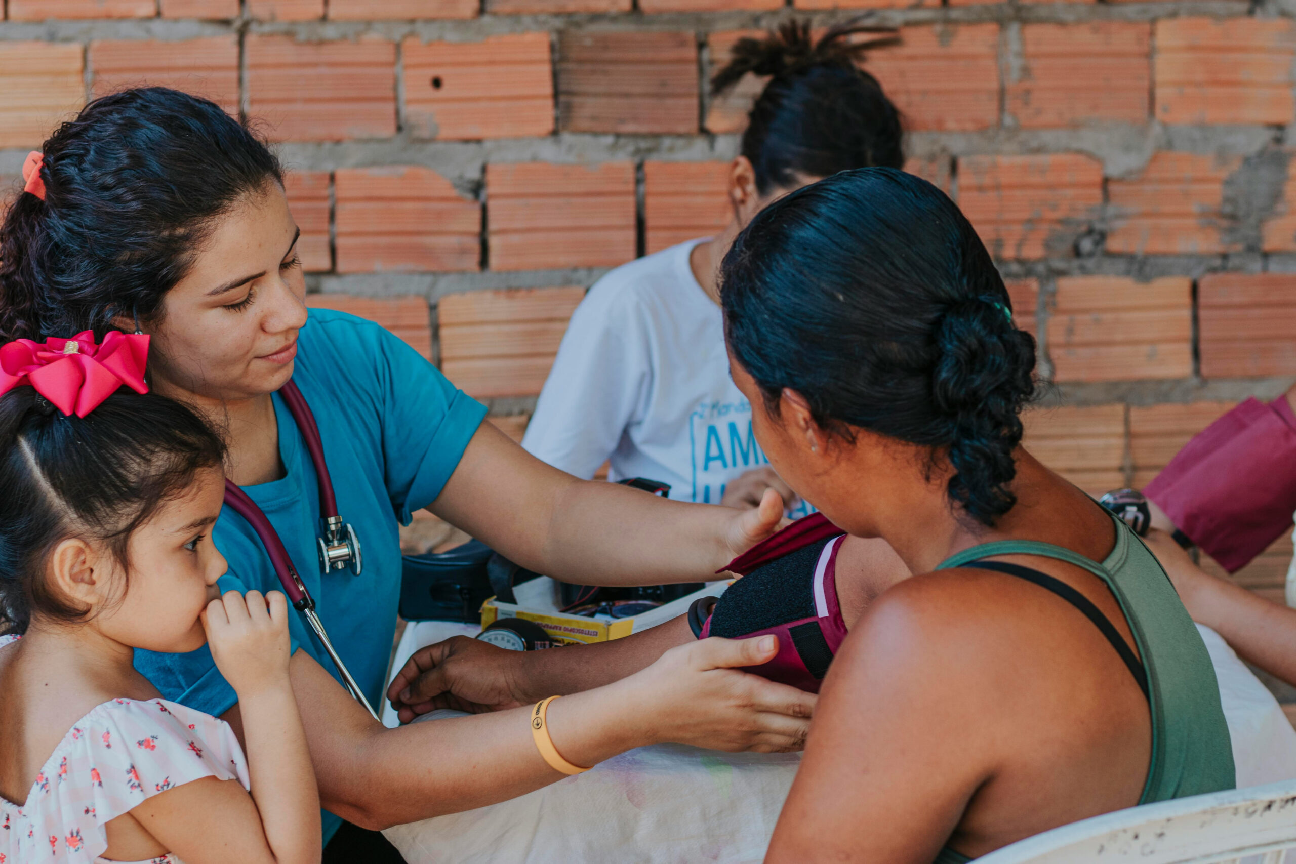 Médica atende uma mãe e sua filha pequena em atendimento comunitário
