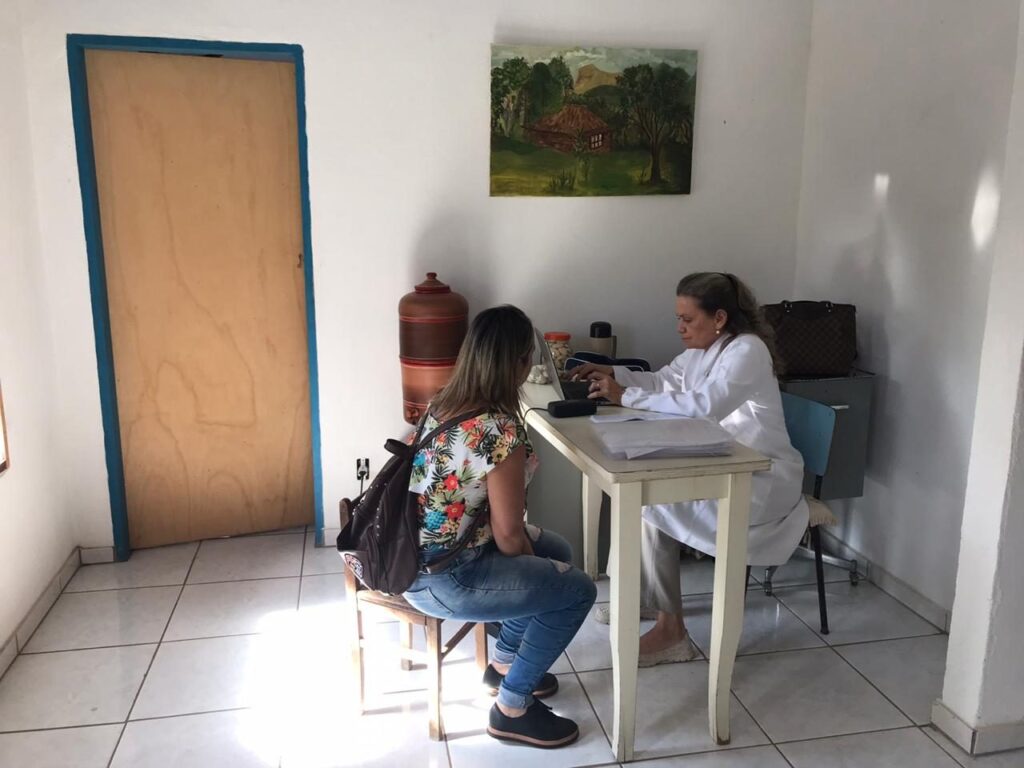 Médica do Instituto Archeus em consulta com paciente em sala simples de atendimento comunitário