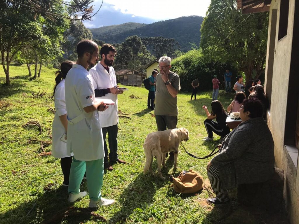 Veterinários atendem cão de morador da comunidade, com montanhas ao fundo